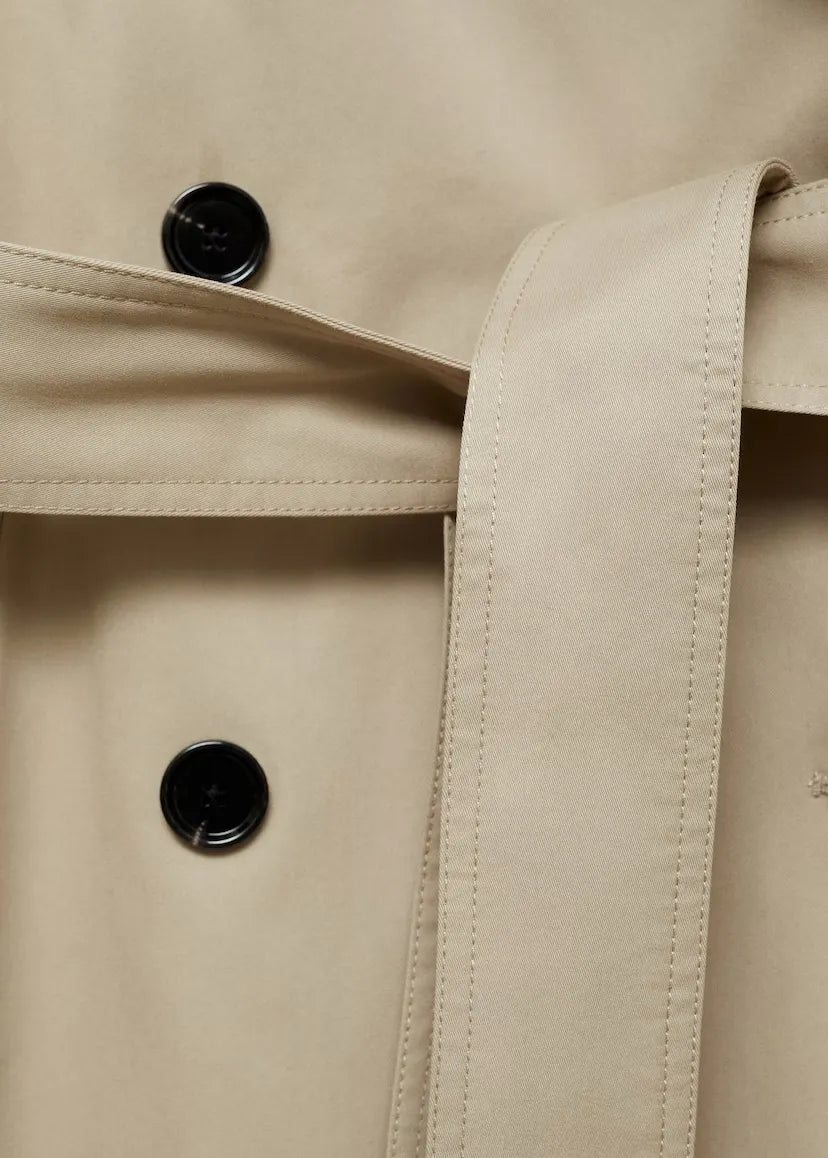 Close-up of a beige trench coat with black buttons
