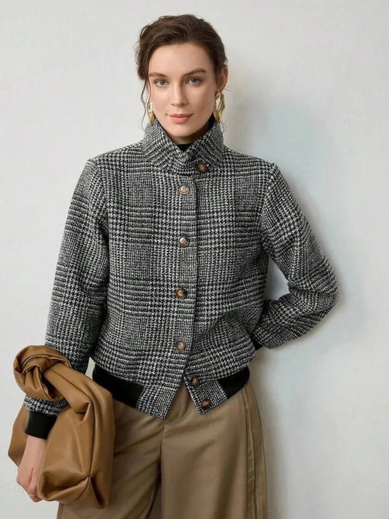 Woman wearing a checkered jacket holding a brown coat against a light background