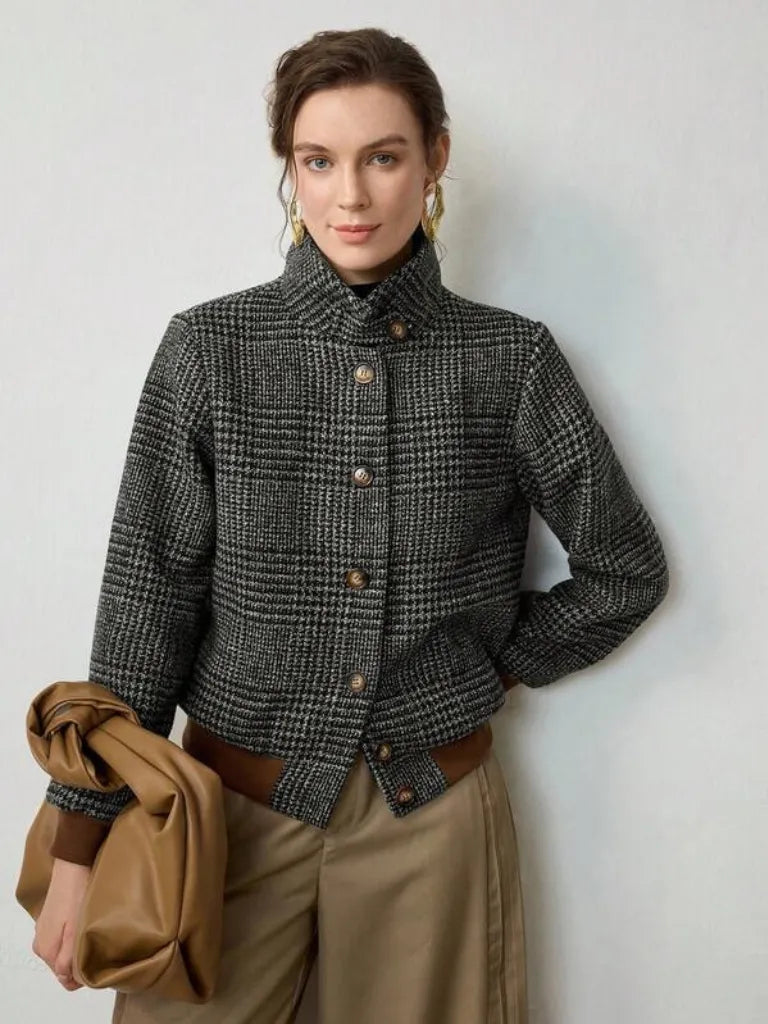 Woman wearing a checkered jacket holding a brown coat against a white background
