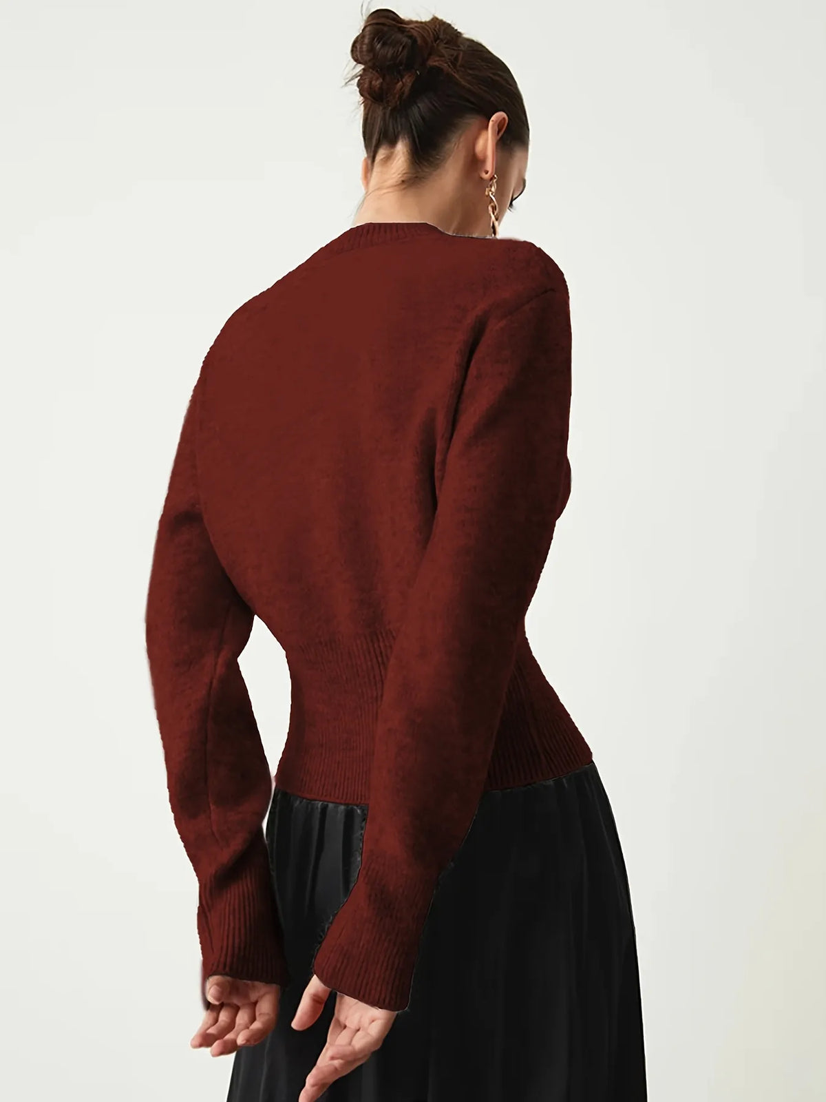 Person wearing a burgundy sweater and black skirt on a white background