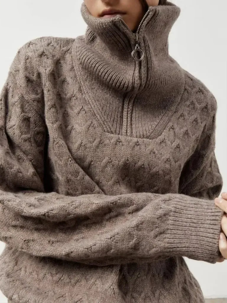 Close-up of a person wearing a brown cable knit sweater with a high collar.