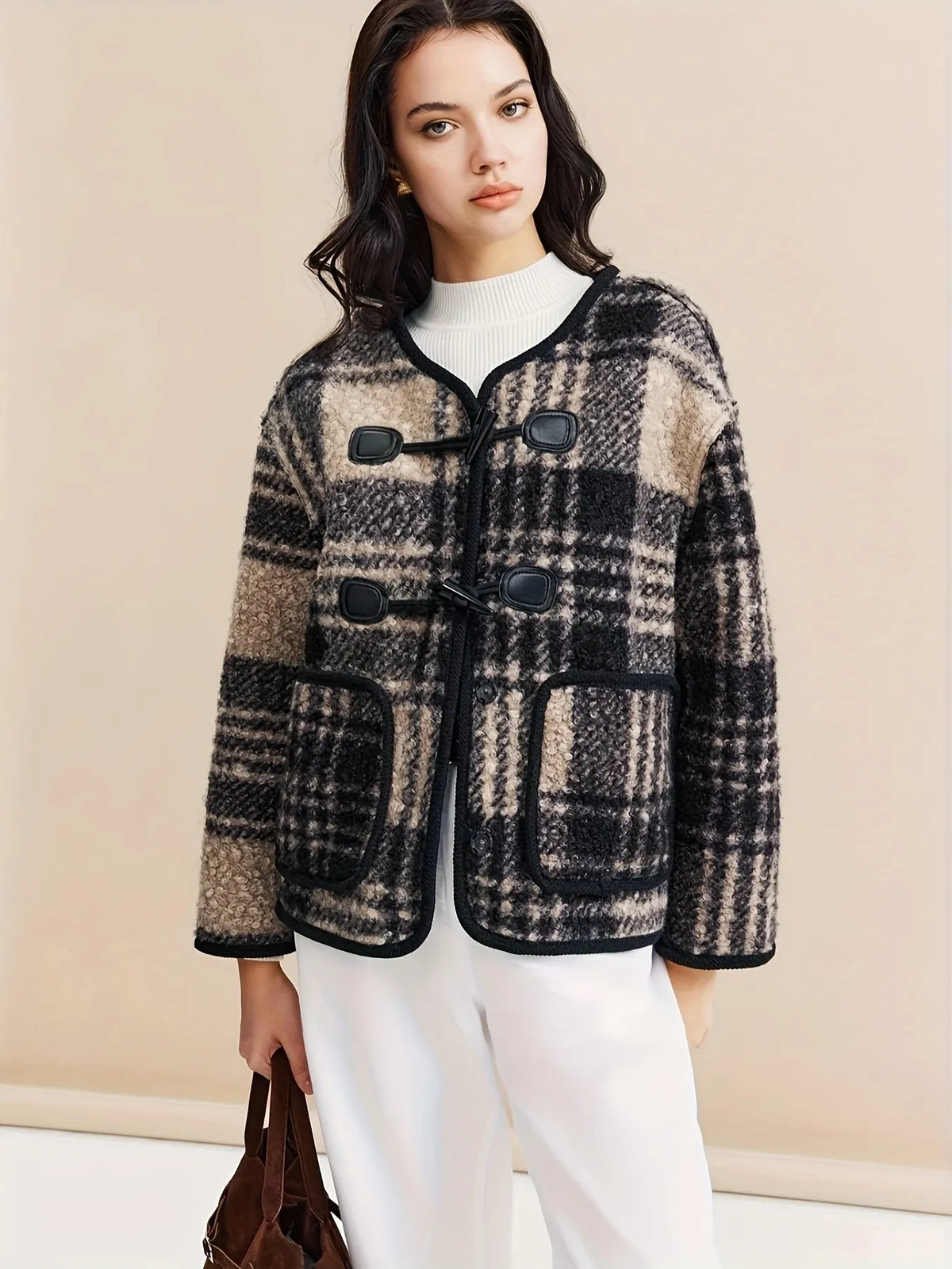 Woman wearing a plaid jacket with a plain background