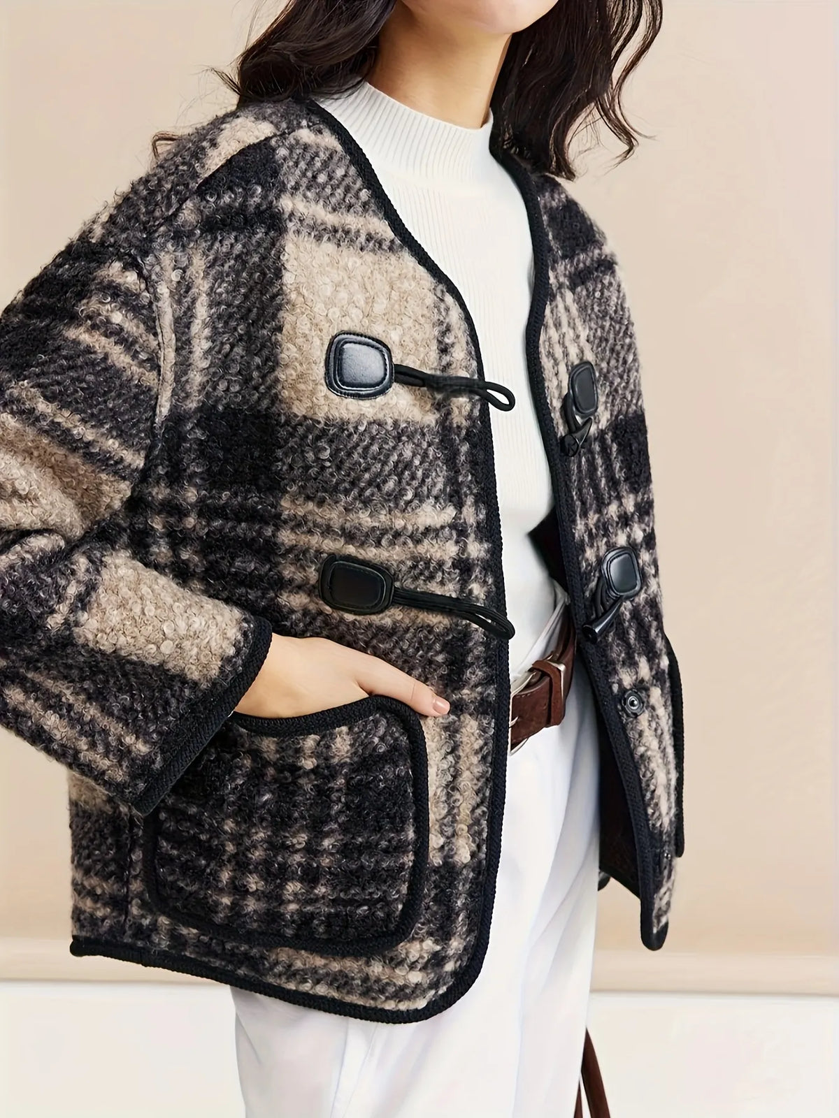 Woman wearing a plaid jacket with a plain background
