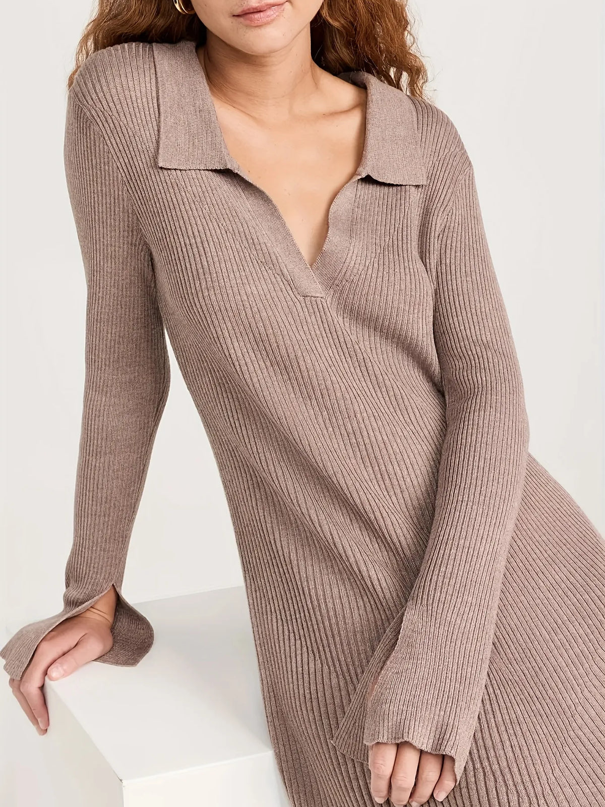 Woman wearing a long brown ribbed dress against a white background